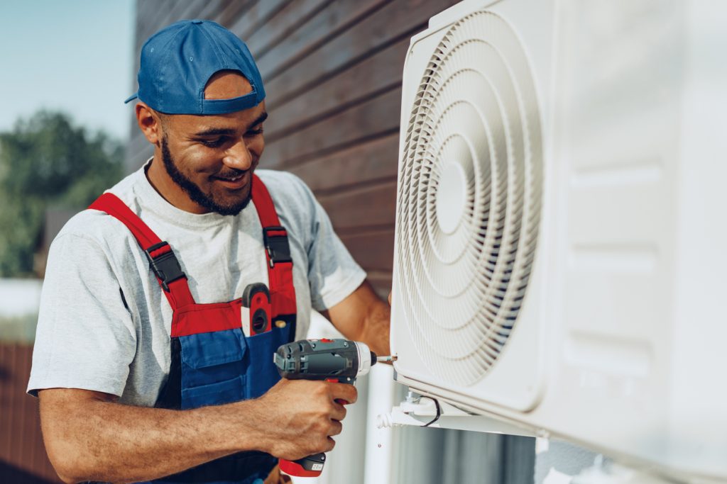 Repairman in uniform installing the outside unit of air conditioner close up